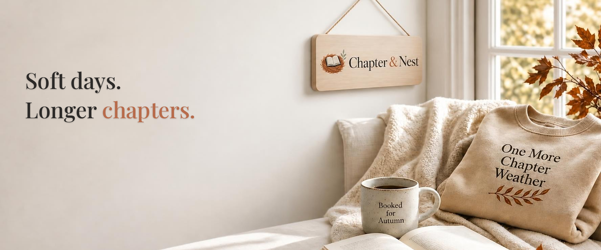 Cozy autumn reading nook with Chapter & Nest hanging wooden logo sign and slogan Soft days. Longer chapters. on the cream wall